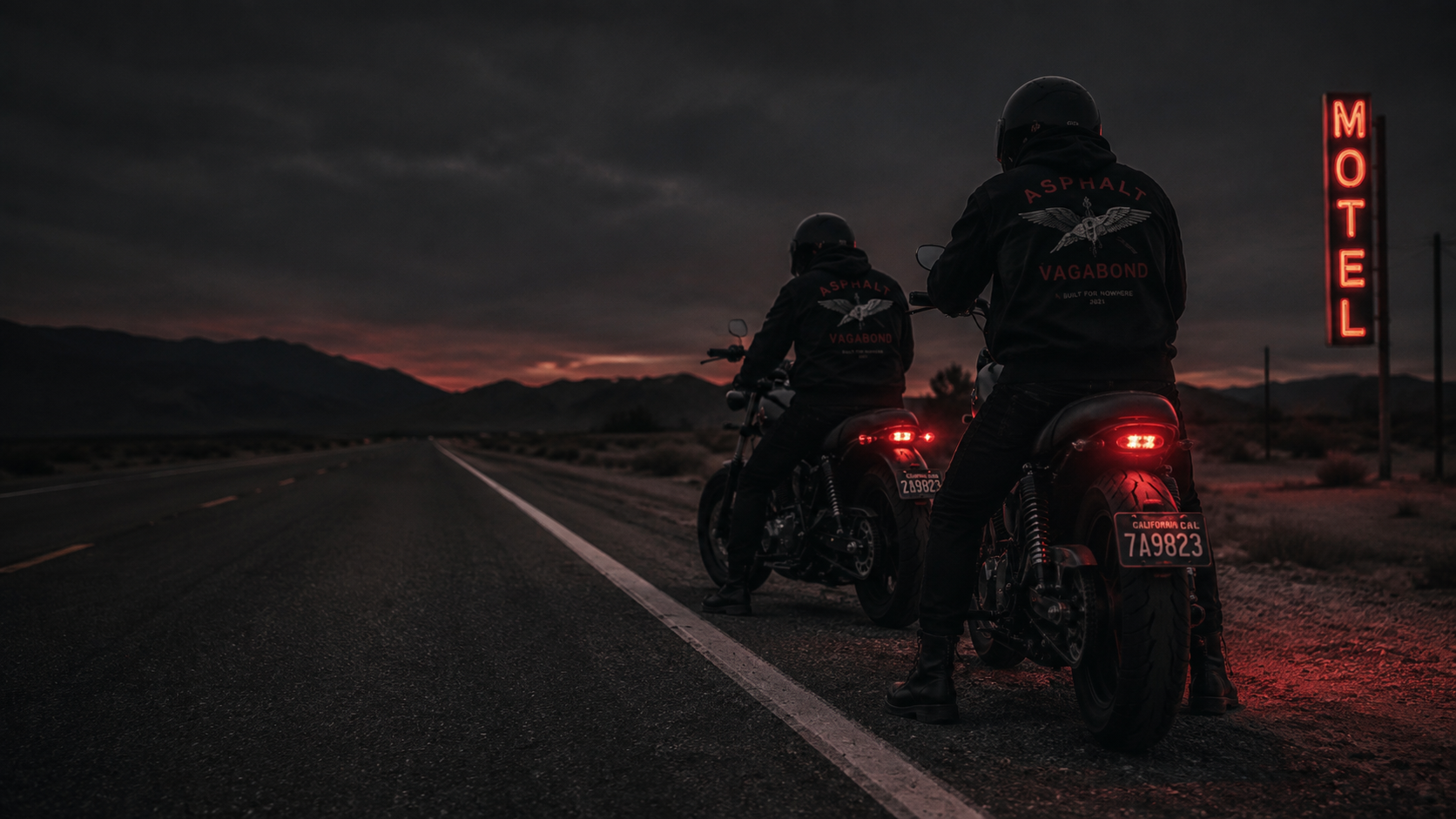 Two Asphalt Vagabond riders stopped with custom motorcycles beside a motel at nightfall